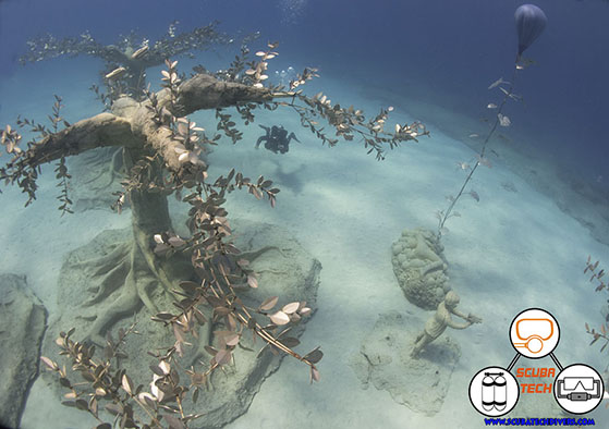 MUSAN underwater museum. Diver under the sculptured tree, free moving kelp sculpture forest and a child of the forest sculture in the picture taken from above