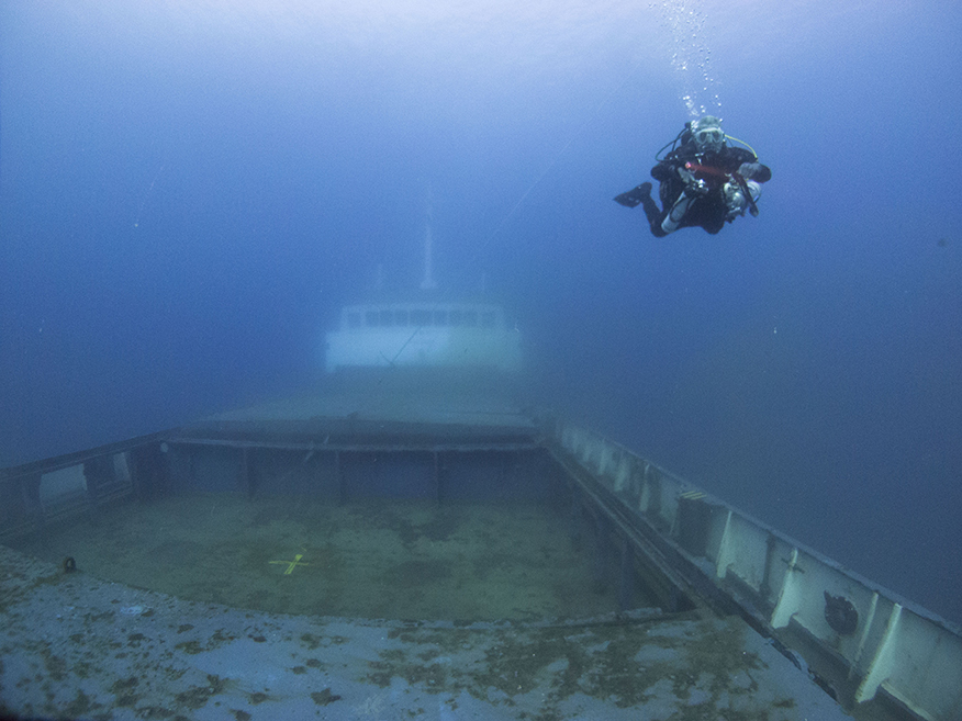 Shot of the Elpida wreck in cyprus. Diver over the cargo hold, in the blue