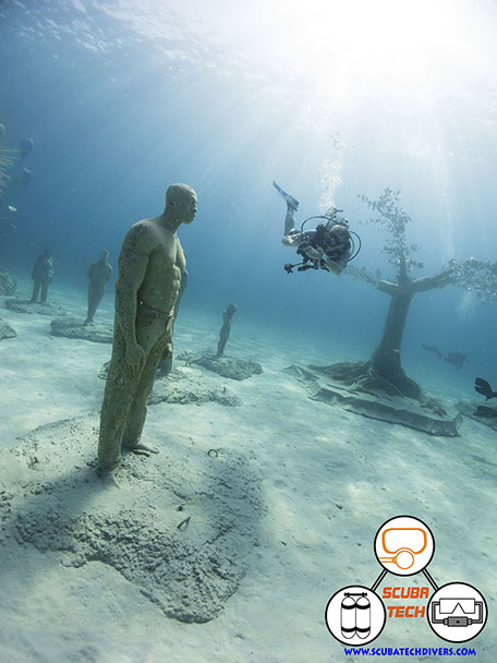 Diver near the trees in the Ayia Napa Sculpture Museum taking a phot of a sculpture